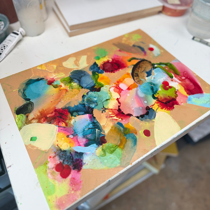 Colorful abstract painting on a table with art supplies in the background