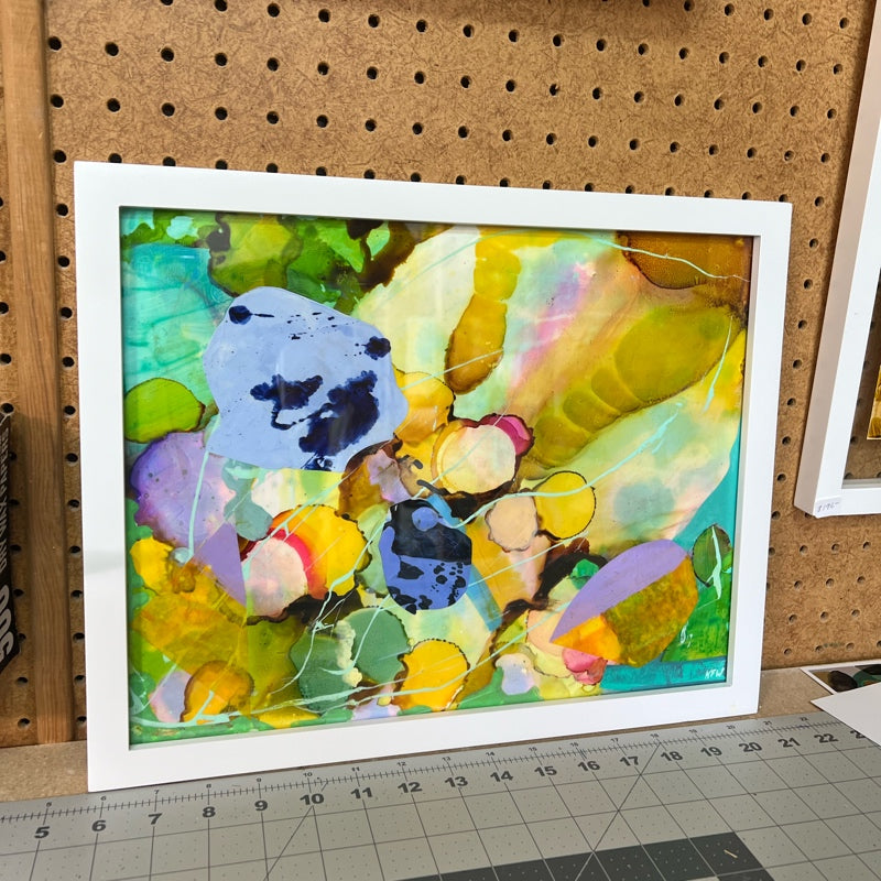 Colorful Abstract art with shapes in a white frame resting on a table