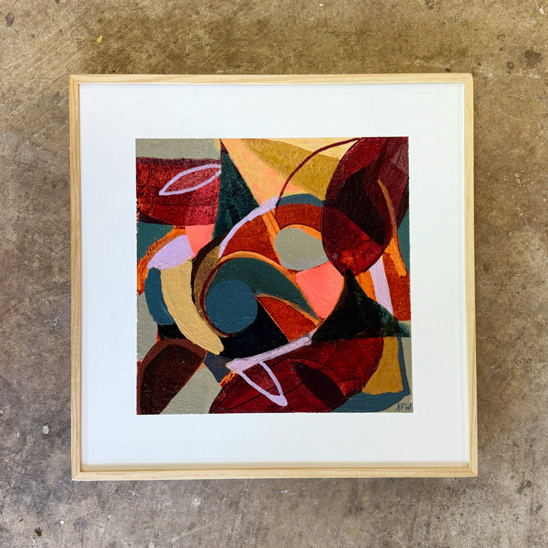Framed abstract artwork with colorful geometric shapes on a textured wall.