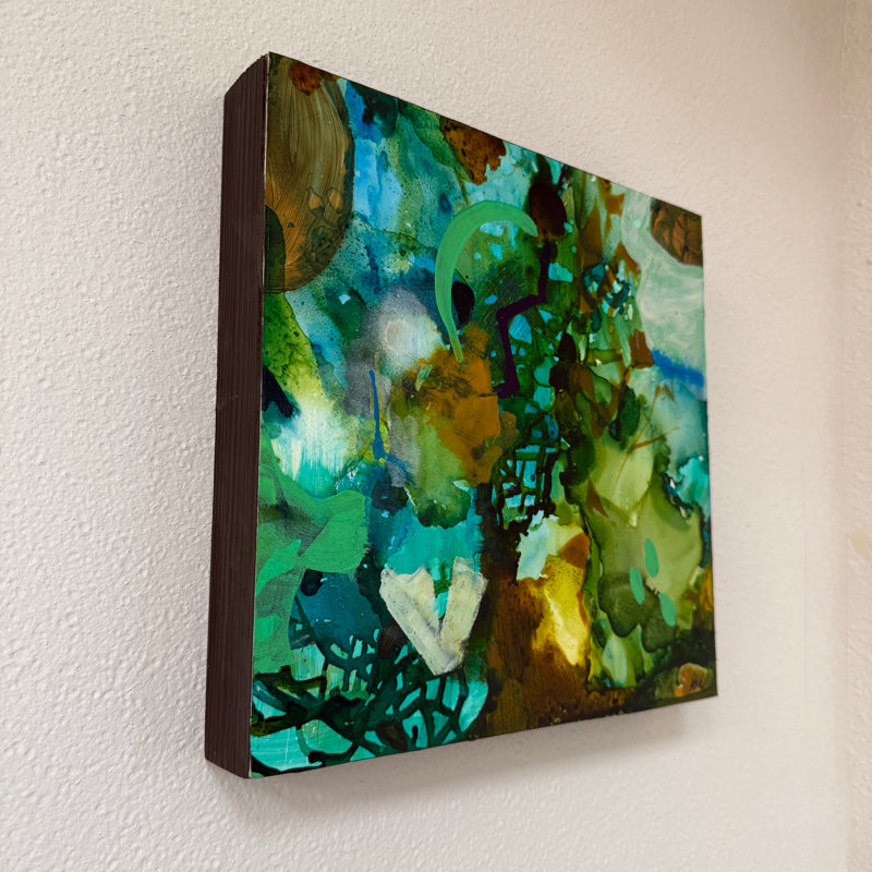 Abstract painting with green and blue tones on a white wall side view