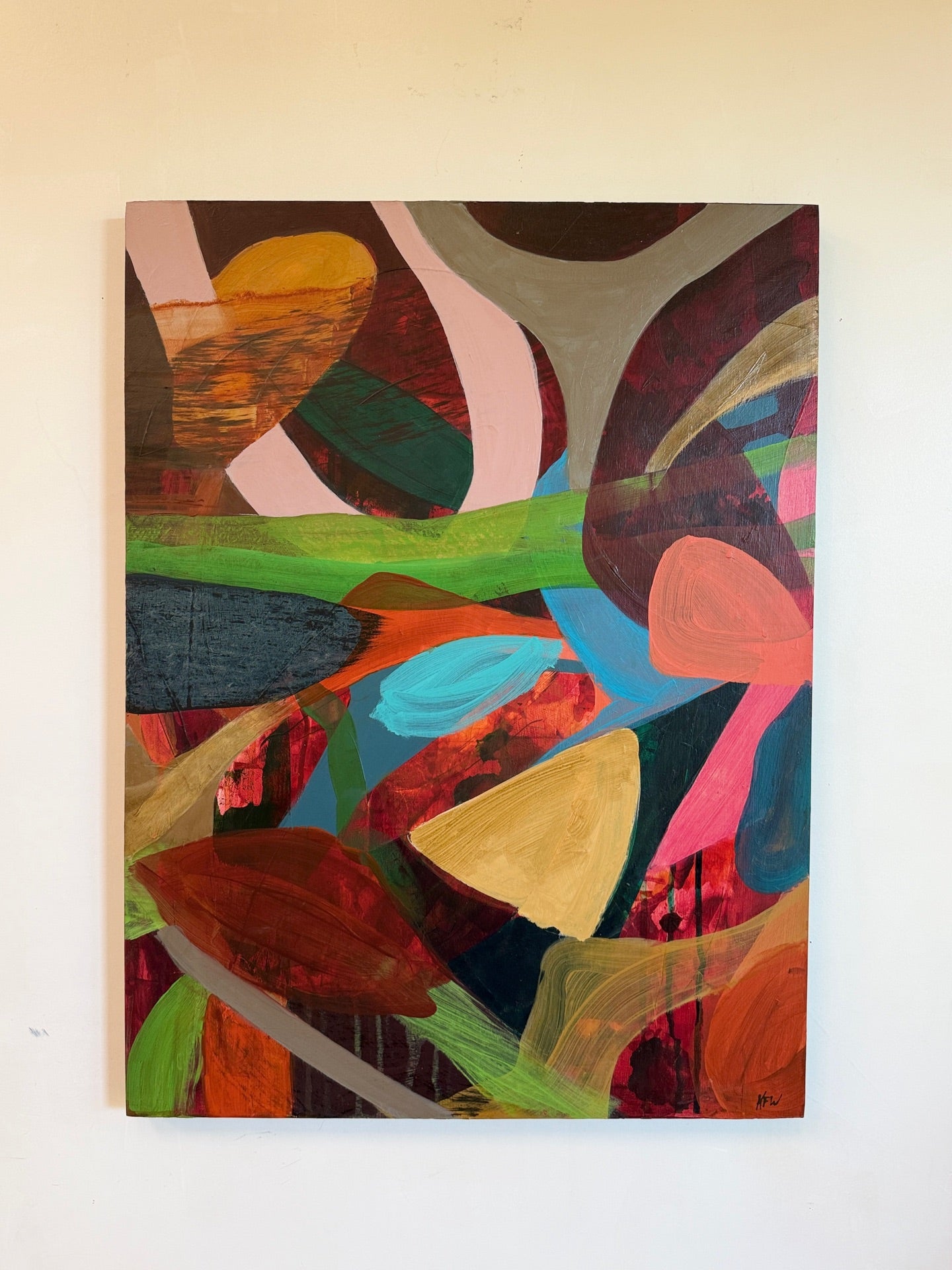 An abstract painting with expressive, layered brushstrokes in a variety of colors including pink, green, blue, brown, orange, and yellow, displayed on a plain off-white wall.