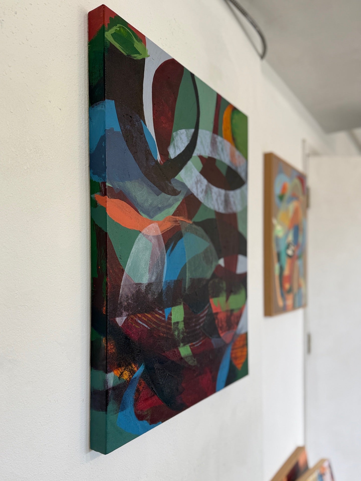 Sideview of abstract artwork with muted colorful shapes on a white wall