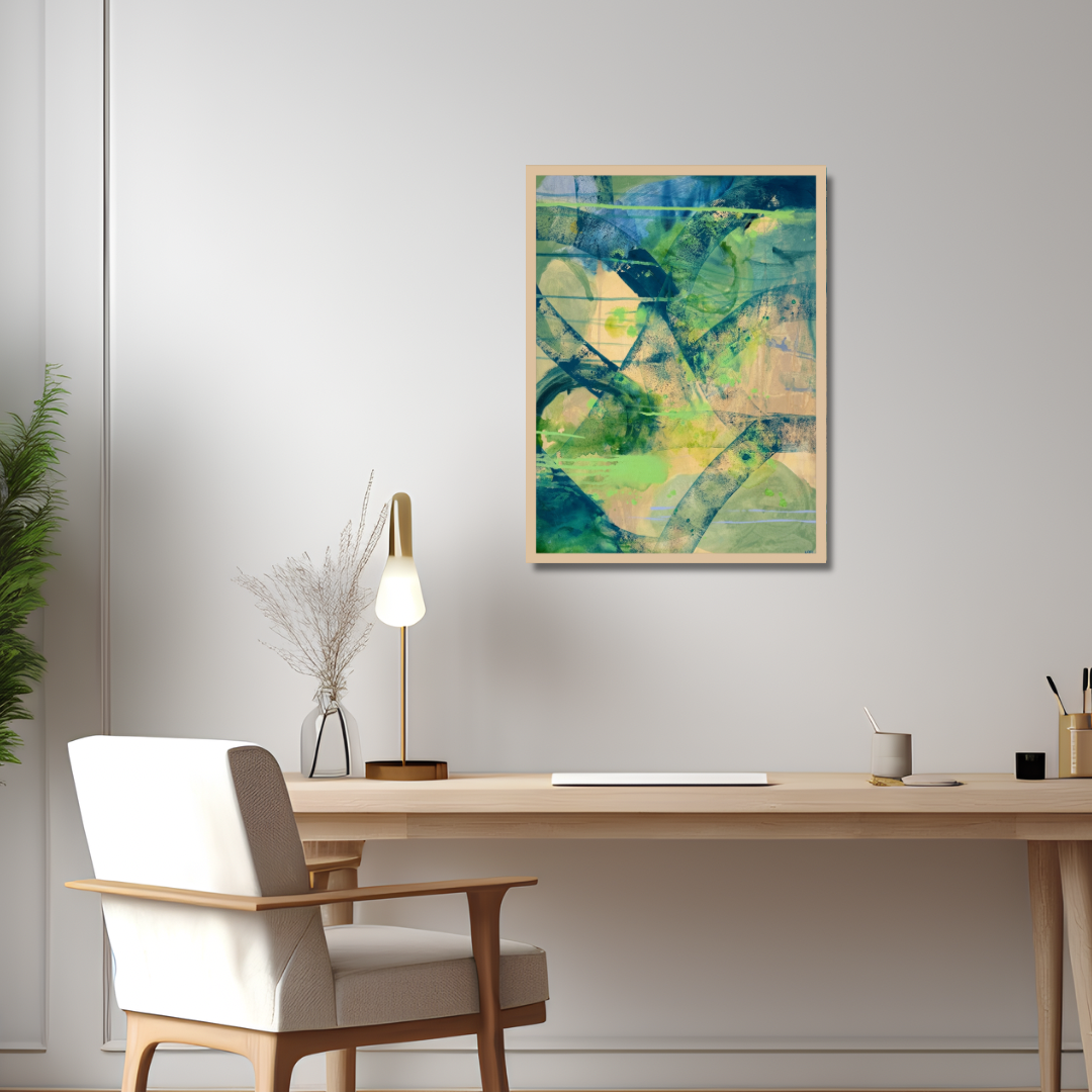 An abstract framed art print featuring green, blue, and yellow brushstrokes, displayed on a light gray wall above a modern wooden desk with a white chair and a gold lamp.